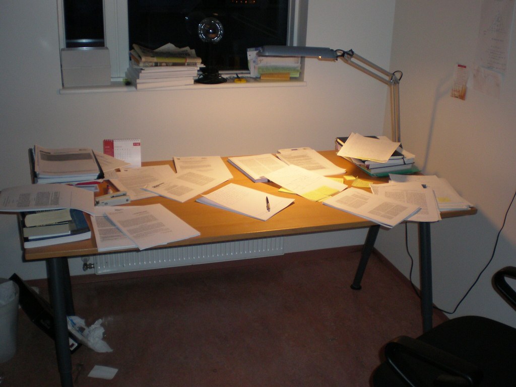 Desk with papers scattered all over, showing a writing process