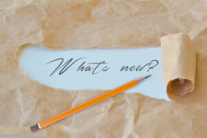 Image of brown paper being torn away to reveal "What's New" written in pencil