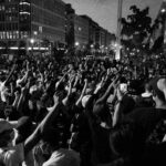 Black and white street scene of protest with people with fists raised.